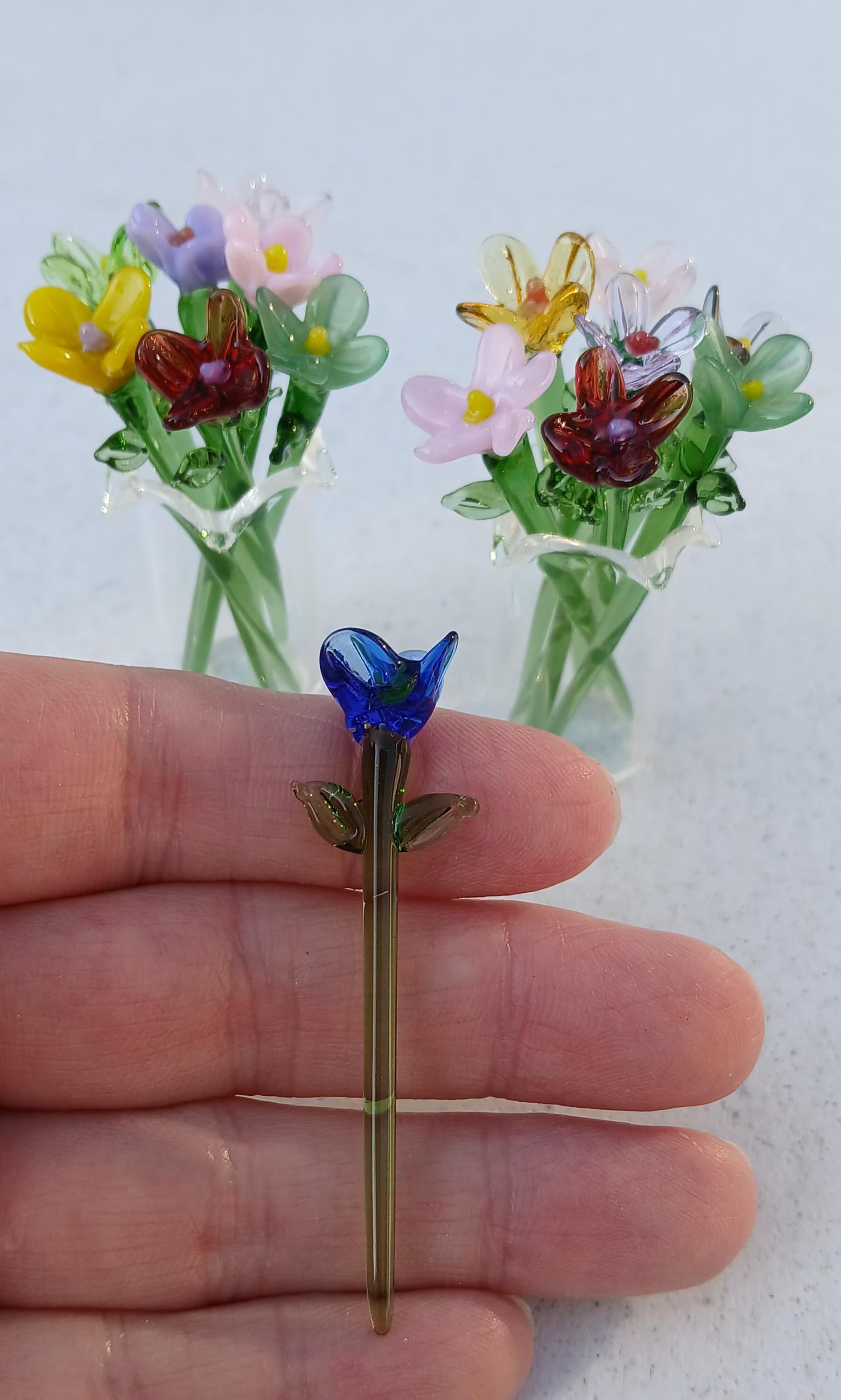 Glass flower held in a hand to show the size of the miniature flowers