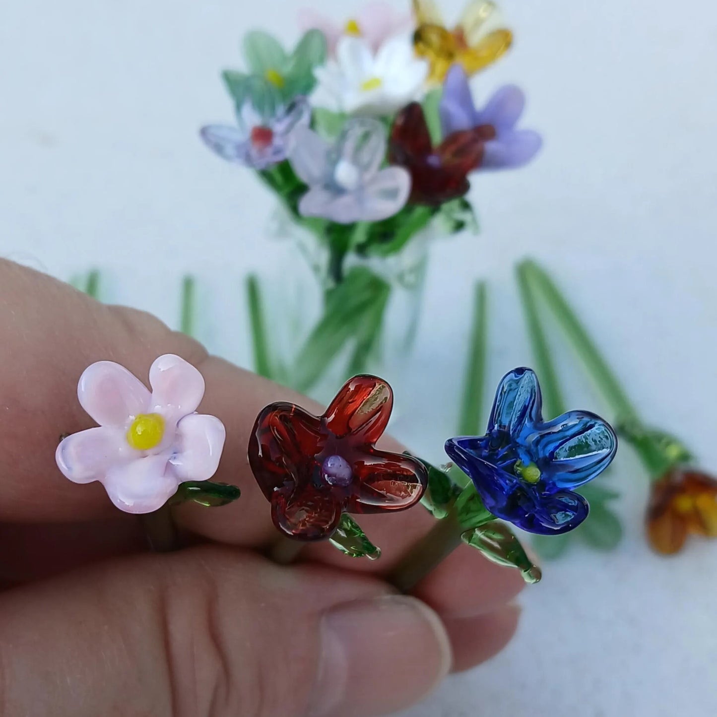 Close-up of pink, red, and blue miniature lampwork flowers, highlighting intricate handmade details