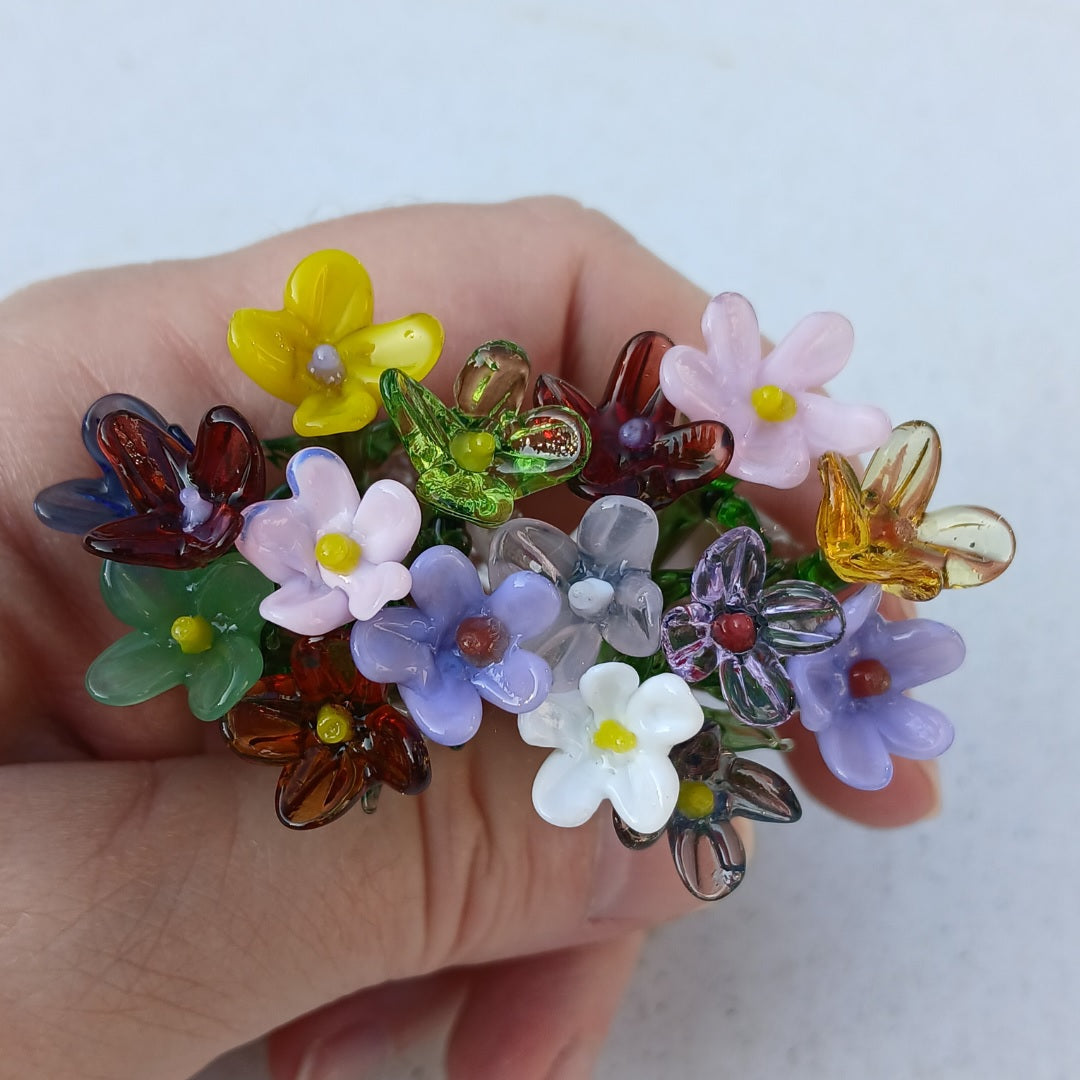 Colorful glass flowers held in a hand against a white background