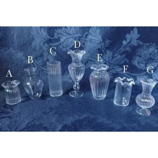Set of 7 different clear glass vases on a textured blue background