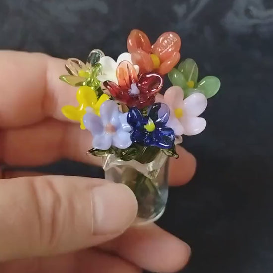 video showing miniature glass flowers in a glass vase, showing size and the colorful bouquet of flowers
