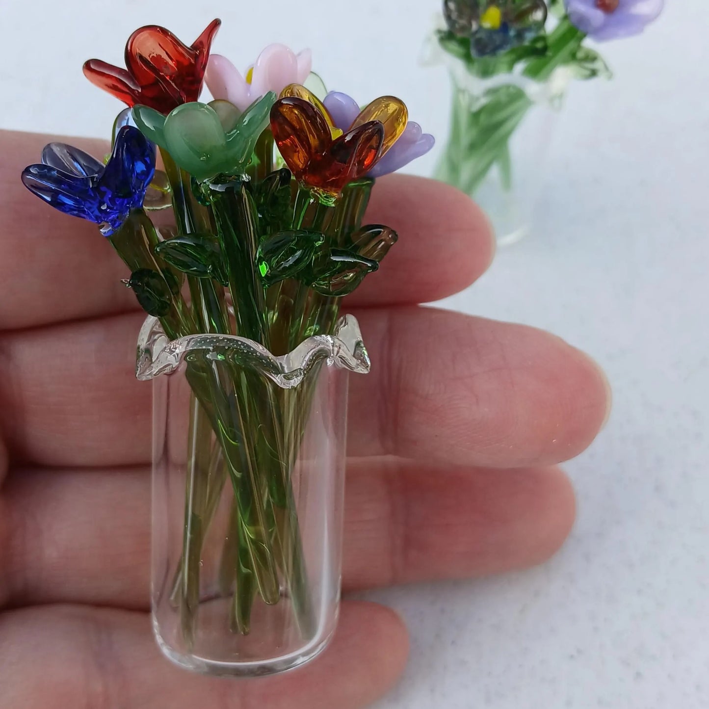 Side view of a miniature glass vase filled with handmade lampwork flowers, showing delicate blooms